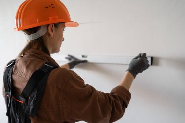 İnşaat alanında çalışırken ya da ev dekorasyonu yaparken ruh seviyesiyle duvar ölçen bir kadın müteahhit. Boşluğu kopyala