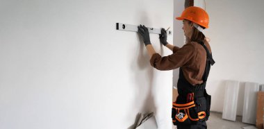 İnşaatçı kadın koruyucu başlık takıyor. Ruh seviyesini koruyor. Tamir, yenileme ya da inşaat işleriyle uğraşıyor. Boşluğu kopyala