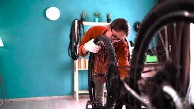 Evde bisiklet tamir eden genç bir kadın ingiliz anahtarıyla bisiklet tekerleği tamir ediyor. Hobi ve ÇEVİRİ kavramı