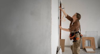 Ev Yenileme sırasında duvarları ölçmek için ruh seviyesini kullanan kadın tamirci. Boşluğu kopyala