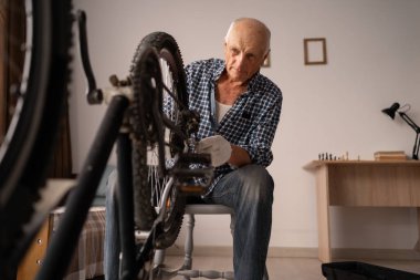 Aktif kıdemli adam evde bisiklet tamir ediyor. Boş vakitlerde bisiklet sürmek. Bisiklet bakım tekerlerini tamir etmek için ingiliz anahtarıyla çalışan emekli bir tamirci. Yakın plan.