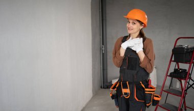 Tulumlu ve miğferli genç müteahhit, merdiven altyapısına sahip inşaat alanında dururken el ele tutuşuyor. Pankart. Boşluğu kopyala