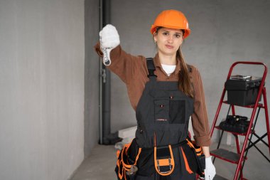 Tatmin olmamış üzgün müteahhit sert bir şapka takıyor ve başparmağıyla hoşlanmadığı jestler yapıyor. Boşluğu kopyala