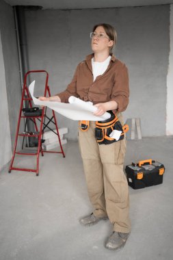 Alet kemeri takmış bir kadın oda planlarını tutuyor, evini yenilemeyi planlıyor. Ev tamiri. Boşluğu kopyala