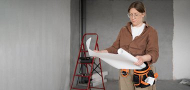 Tamirci ya da inşaat işçisi ev tadilatı sırasında planları inceliyor. Pankart. Boşluğu kopyala