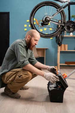 Beyaz sakallı adam evde bisiklet tamir eden aletlerle alet kutusunu açıyor. Motosiklet bakım kavramı