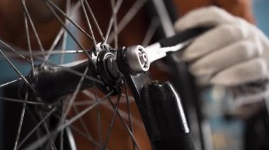 Evde bisiklet tamir ediyorum. İngiliz anahtarıyla bisiklet tekerleğini tamir etmek, yakın plan. Bisiklet parçaları. Boşluğu kopyala