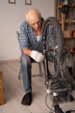 DIY ve hobi konsepti. Emekli bisikletçi, tamirat sırasında bisikleti kontrol ediyor. Boşluğu kopyala