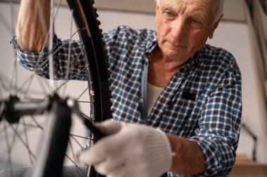 Aktif son sınıf erkek bisikletçi ingiliz anahtarıyla bisiklet tekerleğini kontrol ediyor. Evde hasarlı bisiklet tekerleği var. Yakın plan.