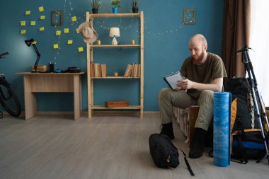 Dağ yürüyüşü turuna hazırlanmadan önce evdeki dağ yürüyüşü gezisinden önce yolcu listesi yazıyor.