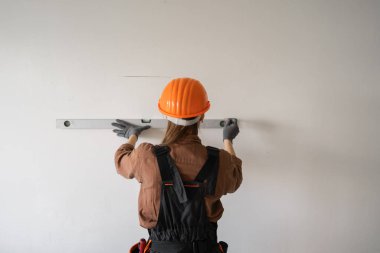 İnşaat alanında çalışırken ya da ev dekorasyonu yaparken ruh seviyesiyle duvar ölçen bir kadın müteahhit. Boşluğu kopyala