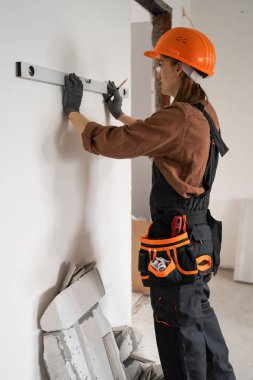 İnşaatçı kadın koruyucu başlık takıyor. Ruh seviyesini koruyor. Tamir, yenileme ya da inşaat işleriyle uğraşıyor. Boşluğu kopyala