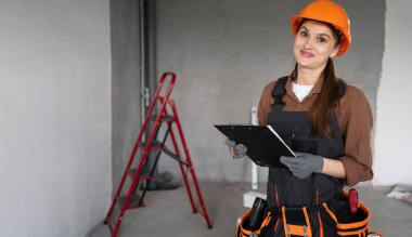 İnşaat alanında çalışan ve kameraya bakan kadın inşaat işçisinin portresi. Yakın plan.
