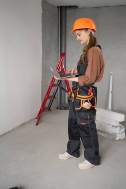 Tamirci kadın dizüstü bilgisayarla yenileme hakkında bilgi arıyor. İnşaat ve onarım konsepti