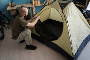 Dağlarda bir yürüyüşe hazırlanıyorlardı. Evde kamp yapmak için çadır hazırlıyorum. Sakallı adam yürüyüşçüsü eve yolculuk için hazırlanıyor. Turizm, yürüyüş ve seyahat konsepti. Boşluğu kopyala