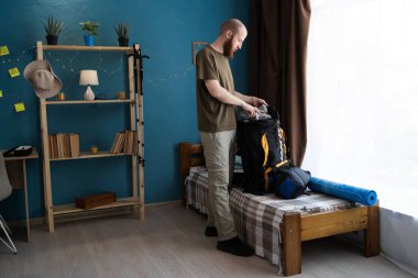 Evde yürüyüş yapmak için sırt çantası hazırlayan bir sırt çantası. Yürüyüşe hazırlanma kavramı. Boşluğu kopyala