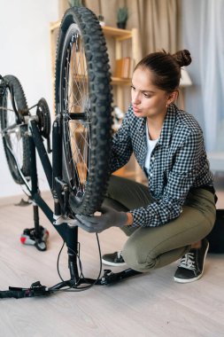 Motosiklet arızası. Evde bisiklet tekerleğini tamir eden genç bir kadın. Boşluğu kopyala
