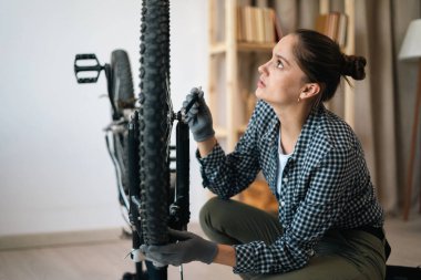 Aktif bir kadın bisiklet bakımı yapıyor, pedalları ayarlıyor. Boşluğu kopyala