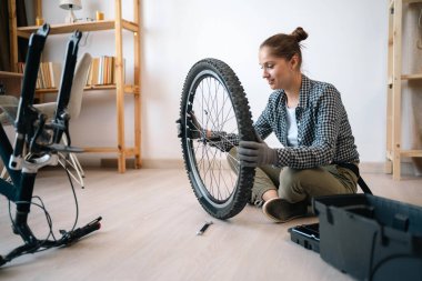 Dışarıda bisiklet sürmek için bisiklet kullanan bir bayan. Evde bisiklet lastiği ayarlayan bir kadın. Boşluğu kopyala