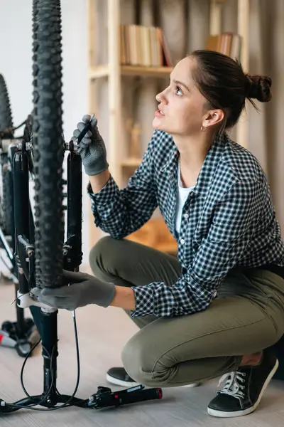 Aktif bir kadın bisiklet bakımı yapıyor, pedalları ayarlıyor. Boşluğu kopyala