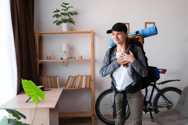 Sırt çantasıyla gezmeye hazır samimi bir bayan gezgin göğsüne katlanmış el ele tutuşuyor. Duygusal samimi turist kadın evde minnettarlık işareti gösteriyor. Boşluğu kopyala