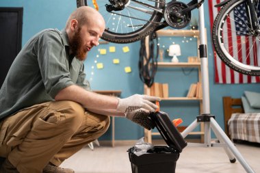 Beyaz sakallı adam evde bisiklet tamir eden aletlerle alet kutusunu açıyor. Motosiklet bakım kavramı