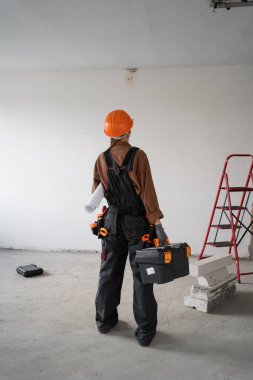 Tadilat, inşaat konsepti ve ev içinde tadilat yapmaya hazırlanan kadın müteahhitlerin eski evdeki alet çantasının arkasında duran tamirci.