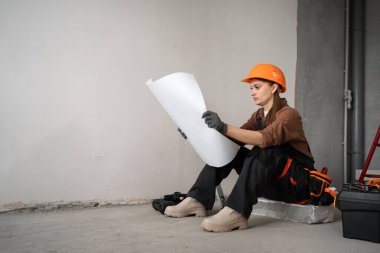 Kadın müteahhit, tadilattan önce oturma odasının planlarını okuyor. Metin için boşluk