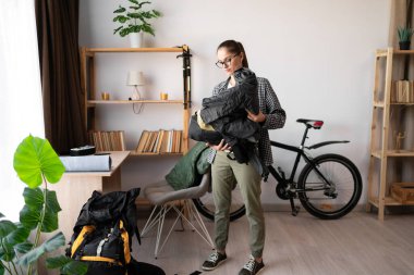 Dişi sırt çantalı sırt çantası paketleyicisi, ev içi gezisi için sırt çantası hazırlıyor. Boşluğu kopyala