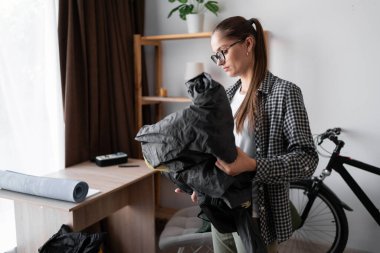 Dişi sırt çantalı sırt çantası paketleyicisi, ev içi gezisi için sırt çantası hazırlıyor. Boşluğu kopyala