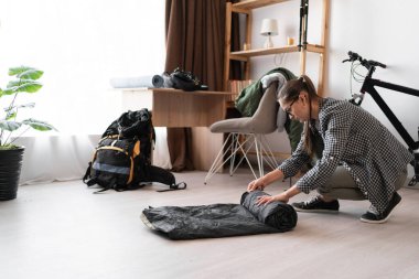 Kamp yapmak için gözlüklü bayan sırt çantalı sırt çantası, ev içi seyahati için bavul hazırlıyor. Boşluğu kopyala