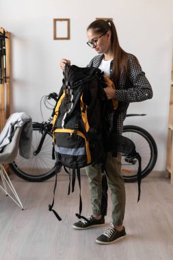Tişörtlü, gözlüklü, sırt çantalı, gezisi için gerekli teçhizatı olan kadın bir sırt çantası. Seyahat, turizm ve yürüyüş konsepti