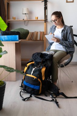 Sırt çantalı kadın tökezlemeye hazırlanıyor. Yolculuk için kontrol listesini kontrol et. Seyahat, yürüyüş ve tatil konsepti.