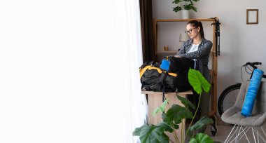 Yürüyüş, dağ gezisi için bir sırt çantası hazırlamak, bir bayan yürüyüşçü evde doğa turuna hazırlanıyor. kopyalama alanı. Pankart