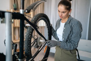 Kadın tamirci arka tekerlek ayarlaması. Ev atölyesinde çalışan tamirci kadın. Boşluğu kopyala