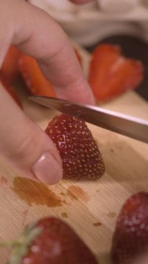 Şef ahşap kesme tahtasıyla taze çilek dilimliyor. Restoranda dilimleme tahtasıyla çilek kesmek. Dikey video