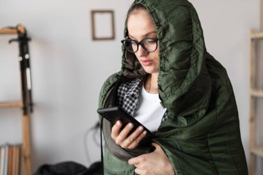 Woman in a sleeping bag with smartphone at home. equipment for recreation in tourism and travel. copy space