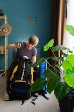 middle aged woman packing hiking backpack at home before mountain journey, preparing equipment for trekking adventure, indoor scene of personal travel planning and readiness