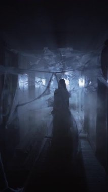 Korkunç kadın Cadılar Bayramı zombisi. Yaralı ölümsüz kız yüzünü yapıyor. Karanlık koridorda elinde örümcek ağıyla kameraya bakıyor. Boşluğu kopyala