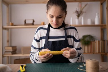Önlüklü İspanyol bir zanaatkar atölyedeki masanın üstünde doğal mum yapıyor. Boşluğu kopyala