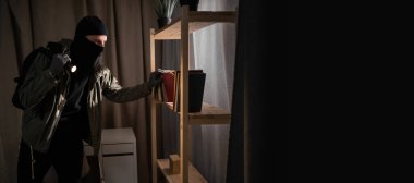 Burglar or intruder with flashlight. Illegally breaking. Male robber wearing black balaclava steals money from apartment. Thief committing theft. Criminal offence. burglary and housebreaking concept