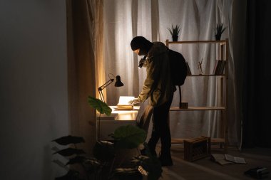 Burglar or intruder with flashlight. Illegally breaking. Male robber wearing black balaclava steals money from apartment. Thief committing theft. Criminal offence. burglary and housebreaking concept