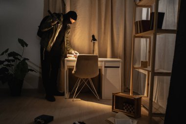 Burglar or intruder with flashlight. Illegally breaking. Male robber wearing black balaclava steals money from apartment. Thief committing theft. Criminal offence. burglary and housebreaking concept