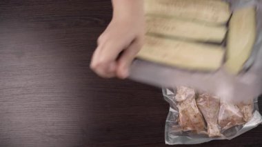 Tavuk bacağı, patlıcan, mantar ve narenciye dilimleri de dahil olmak üzere çeşitli vakumlu yiyecekler dondurmak ve uzun vadeli depolamak için plastik poşetlere dolduruldu. Ev mutfağı gıda koruma süreci.