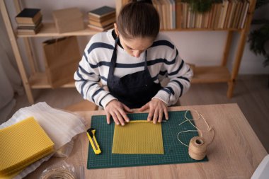 Evinde el yapımı mum yapmak için önlük giyen kadın çevre dostu diy hobisinin, yaratıcı zanaat sürecinin, küçük işletme ve yaşam tarzı kavramının tadını çıkarıyor.