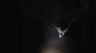 Korku filmi konsepti. Beyaz çarşaflı kadın eski evin koridorunda dikkatsizce yürüyor. Boşluğu kopyala