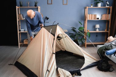 Yaşlı gezgin içeride çadır kuruyor, kamp, yürüyüş ya da keşif gezisinden önce çadır bileşenlerini kontrol ediyor..
