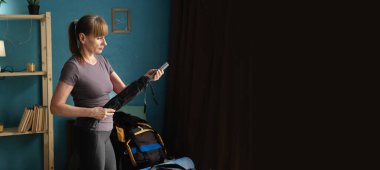 Sırt çantalarını toplarken çadır direğini tutan kadın yürüyüşçü, yürüyüş ekipmanlarını kontrol ediyor ve dağ turizmi konsepti, keşif, tek başına yolculuğa hazırlık yapıyor.