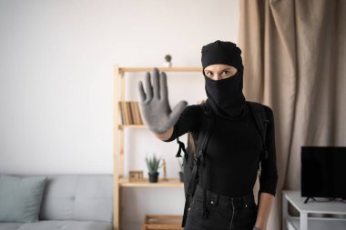 Kadın hırsız ya da siyah kar maskesi takan hırsız kameraya bakarken el hareketiyle durduğunu gösteriyor. Boşluğu kopyala