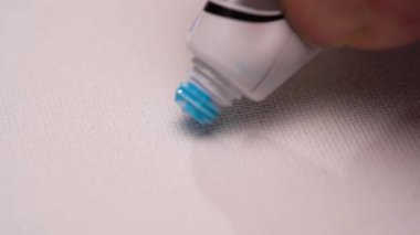 Küçük tüpten mavi boya damlasını tuvale sürüyorum. Yaratıcılığı işlemek soyut yağlı boya resim, makro. Sanat eserinin bir parçası. Yakın çekim görünümü